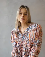 Sweater de punto con diseño étnico multicolor, cuello redondo y detalle de flecos en los hombros. Presenta mangas largas y un ajuste holgado.