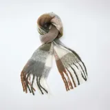 Bufanda de tejido suave con diseño de cuadros en tonos tierra, incluyendo marrón, verde oliva, gris y blanco. Presenta terminaciones con flecos largos en los extremos.