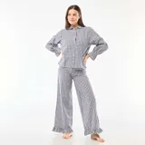 Pijama de dos piezas confeccionado en popelina con estampado de cuadros vichy. Incluye una camisa de manga larga con cuello camisero, cierre frontal de botones y puños con volados, y un pantalón de corte recto con terminación de volado en el ruedo.