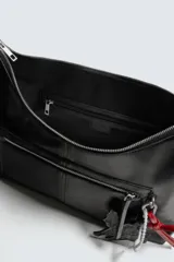 Bolso tipo bandolera de cuero sintético negro con acabado brillante. Presenta un compartimento principal con cierre de cremallera, un bolsillo frontal con cierre y detalle de charms colgantes decorativos. Incluye asa de hombro ajustable.