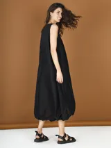 Vestido midi negro de popelina con corte globo y detalle de flor en el hombro.