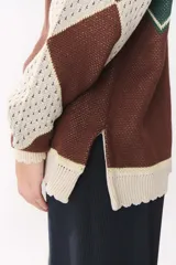 Buzo de tejido de punto con diseño geométrico y combinación de colores en contraste. Presenta cuello redondo, mangas largas y corte oversized.