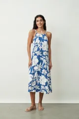 Vestido midi de corte holgado con estampado floral en tonos azul y blanco, presenta escote halter con breteles finos y diseño sin mangas.