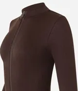 Campera deportiva de corte ajustado, confeccionada en tejido seamless de poliamida y elastano. Presenta cuello alto, cierre frontal con cremallera y textura acanalada.