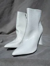 Bota de caña alta color blanco con textura simil cuero y cierre lateral.