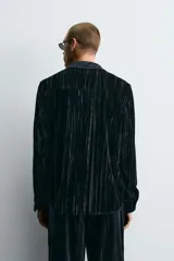 Sobrecamisa de corte relajado confeccionada en tejido de terciopelo fluido con acabado plisado. Presenta cuello solapa, cierre frontal de botones y manga larga con puños abotonados.