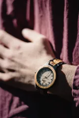 Reloj de pulsera con caja y esfera de madera clara, malla de madera oscura con incrustaciones de madera clara.