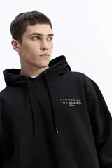 Canguro con capucha color verde oliva, de corte regular, con estampado gráfico multicolor en la espalda que incluye texto y formas abstractas.