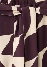 Pantalón largo de corte recto y tiro alto, con estampado abstracto en tonos bordó y crudo. Cuenta con cintura ajustable con elástico y un lazo incorporado para anudar.
