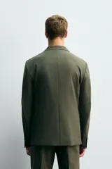 Blazer de corte regular fit confeccionado en tejido ligero con lana. Presenta cuello con solapas de muesca, cierre frontal de botonadura cruzada, mangas largas con botones en los puños, bolsillos de vivo en el pecho y bolsillos de solapa en la cadera.