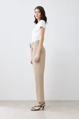 Pantalón de vestir color beige, de corte recto, con pinzas, bolsillos laterales y cinturón con hebilla forrada.