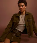 Campera trucker color verde oliva confeccionada en sarga de algodón, con cuello inglés, manga larga, bolsillos delanteros con solapa y abotonado delantero.