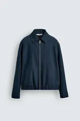 Cazadora boxy fit color azul marino, confeccionada en tejido de algodón. Presenta cuello solapa, manga larga con puño abotonado, bolsillos de vivo en la cadera y bajo elástico. Cierre frontal con cremallera.