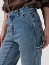 Pantalón de jean tiro alto y pierna recta, confeccionado en denim azul. Presenta diseño clásico estilo carpintero con trabilla lateral para herramientas y bolsillos diagonales.