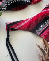 Conjunto de bikini con estampado de rayas horizontales en tonos fucsia, rojo, negro y gris. El corpiño es de estilo triangular con tirantes finos que se atan al cuello y la espalda. La bombacha es de corte colaless con tiras laterales ajustables.