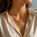 Collar de acero con baño de oro, compuesto por una cadena fina con esferas decorativas y un dije circular con el diseño del árbol de la vida rodeado de cristales.