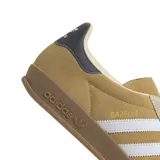 Championes adidas Gazelle Indoor, confeccionados en gamuza color tostado con las icónicas tres tiras laterales en blanco. Presentan suela de goma color marrón, detalle de talón en azul oscuro y el nombre del modelo en dorado.