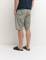 Bermuda chino de corte recto, color verde militar, confeccionada en algodón con elastano. Cuenta con bolsillos laterales de estilo italiano y bolsillos traseros con botón.