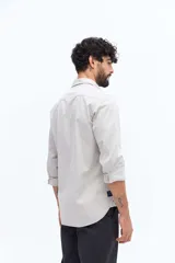 Camisa de gabardina azul marino con efecto stone wash, doble bolsillo frontal con solapa y botón, y fit regular.