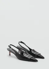 Zapato destalonado de cuero negro con punta fina, detalle de flecos y calados. El tacón mide 5 cm.