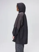 Campera tipo piloto con capucha, cierre frontal con botones y detalle de costuras en zigzag. Presenta cordones ajustables en la cintura y capucha, puños elásticos y logo bordado en el pecho.