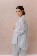 Camisa lila oversize de algodón con bordado floral calado tipo broderie, cuello camisero, manga larga y abotonadura frontal.