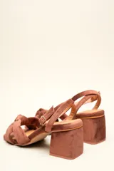 Sandalia de gamuza color beige con taco cuadrado, tira ajustable con hebilla en el tobillo y detalle de nudo en la tira delantera.