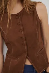 Chaleco de gamuza color caramelo, con cierre frontal de botones y bolsillos laterales simulados.