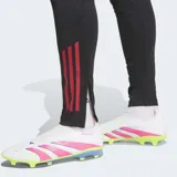 Pantalón de entrenamiento de fútbol Adidas Liverpool FC Tiro 25 Competition, color negro, corte ajustado (slim fit) con puños elásticos y tres franjas verticales rojas en la parte inferior de la pierna. Incluye el escudo del Liverpool FC aplicado con calor en el muslo.