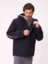 Campera técnica de invierno marca Rusty, color negro, con capucha ajustable, cierre frontal con solapa y bolsillos laterales. Presenta logo de la marca estampado en blanco en la manga y en el pecho.
