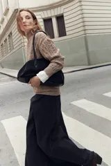 Polerón de cuello alto con diseño de tejido trenzado en relieve, manga larga y puños acanalados.
