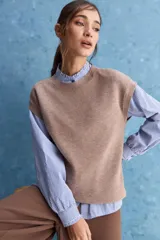 Chaleco de tejido de punto color beige claro, con cuello redondo y diseño de líneas limpias con hombros caídos y terminaciones acanaladas.