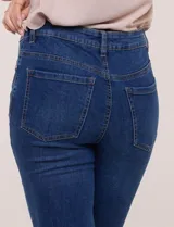 Pantalón capri de jean azul con calce ajustado, tiro alto, cinco bolsillos, cierre frontal con botón y pequeños tajos en los ruedos.