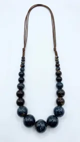Collar regulable de cuentas esféricas de piedra en tonos azul oscuro y marrón, ensartadas en cordones marrones.