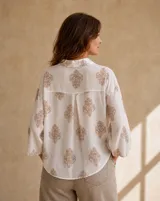 Camisa blanca de manga larga con estampado damasco en tonos camel, cuello camisero y corte holgado.