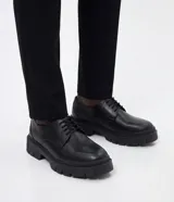 Zapato derby negro de poliuretano para hombre, con diseño robusto, puntera redondeada, cordones y suela tractorada.