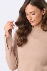 Buzo tejido de lana con cuello alto, diseño de punto grueso, tajos laterales y en puños. Presenta terminaciones acanaladas en puños y cintura, con un parche decorativo en la parte inferior.