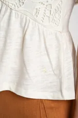 Remera color crudo de algodón con calados, corte al cuerpo y mangas cortas con volados.