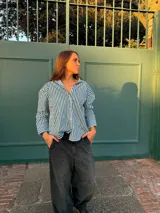 Camisa de corte oversize con estampado de rayas verticales en color negro y blanco, cuello camisero y mangas largas con puños anchos.