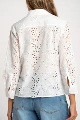 Blusa blanca de manga larga con cuello camisero y bordado tipo broderie anglaise con diseño floral calado.