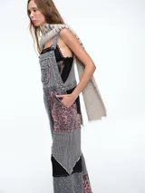 Mono de jean con diseño patchwork que combina diferentes texturas y estampados, incluyendo animal print y motivos geométricos. Presenta corte recto, bolsillos frontales y terminaciones deshilachadas.