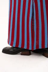 Pollera midi tejida a rayas verticales en color rojo y celeste, con pretina elástica, cordón de ajuste y tajos laterales profundos.