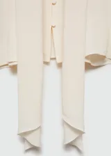 Blusa de tejido fluido en color crema, con diseño oversize, cuello en pico con lazo integrado, cierre frontal de botones y mangas largas con puños abotonados.