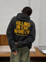 Hoodie canguro con cierre frontal, color negro con efecto acid wash, con capucha y bolsillos tipo canguro. Presenta el texto estampado en amarillo "Now You Do What They Told Ya" en el pecho.