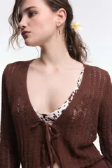 Cardigan tejido de punto calado color blanco, con mangas largas y cierre frontal con lazos.
