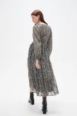 Vestido midi de corte evasé con estampado animal print en tonos oscuros. Presenta escote en V cruzado, mangas largas con puños y falda con volados escalonados.