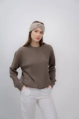 Vincha de lana color beige, tejida a mano, con diseño trenzado en el frente.