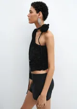 Blusa asimétrica de terciopelo negro con textura de flores en relieve, diseño de un solo hombro con manga larga y detalle de lazo con flor en el cuello.