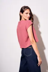 Remera gris de algodón con poliéster, corte crop, mangas cortas y bolsillo en el pecho.