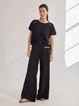 Pantalon de tiro medio-alto con pierna ancha, confeccionado en tela de rayón y poliéster. Presenta bolsillos plaque frontales, costuras a contratono y cierre frontal con botón.